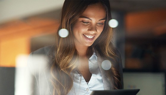 A woman looking at a tablet and smiling.