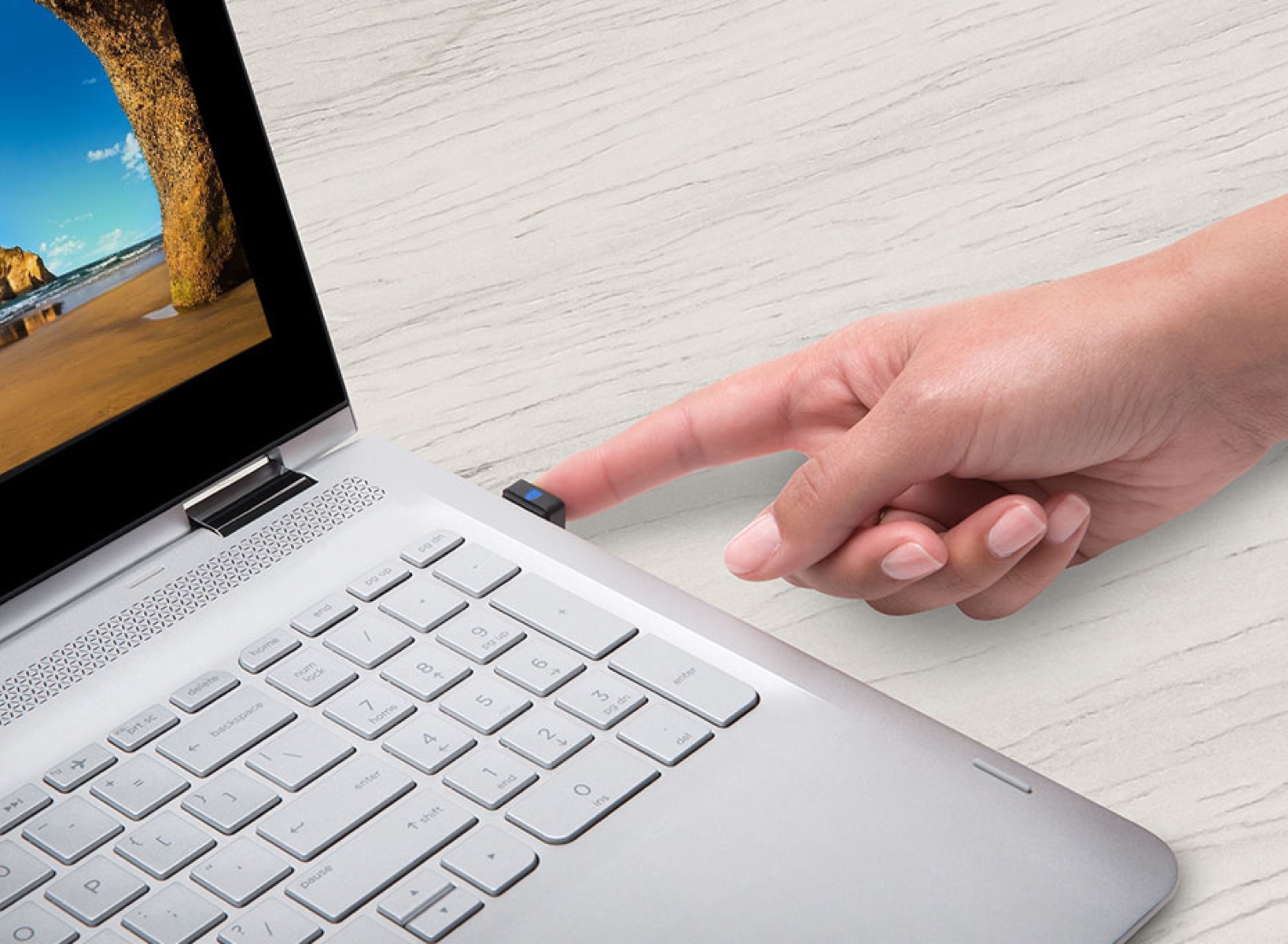 Woman using her finger and a kensington verimark lock to unlock her laptop.