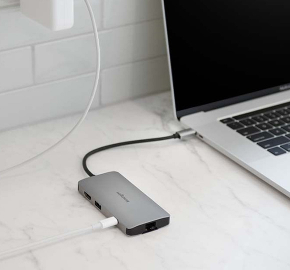 Close up partial view of a MacBook and a Kensington SD5780T Thunderbolt™ 4K/6K  Docking Station on a wooden desk.